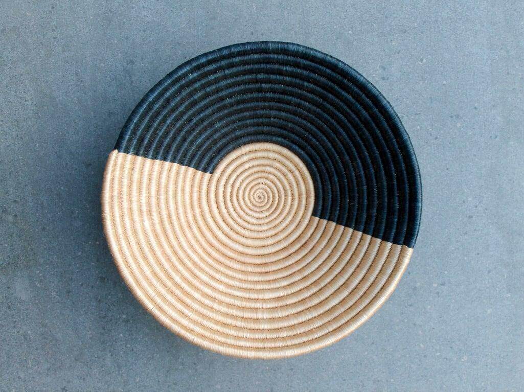 Ethical black and natural woven bowl on grey background